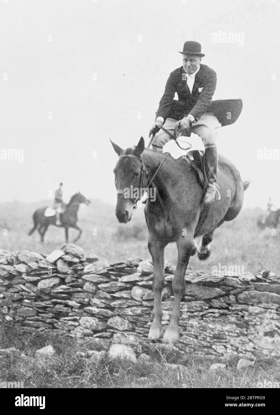 America's hunting, Minister to Eire. Mr John Cudahy , newly appointed United States Minister to Eire (Ireland) is a keen follower of the hunt and has rapidly become very popular in hunting and social circles in County Dublin. Photo shows, Mr John Cudahy , leaves his saddle as his mount takes a stone wall while out with the North Kildare Hounds at Punchestewn, Eire. 4 January 1938 Stock Photo