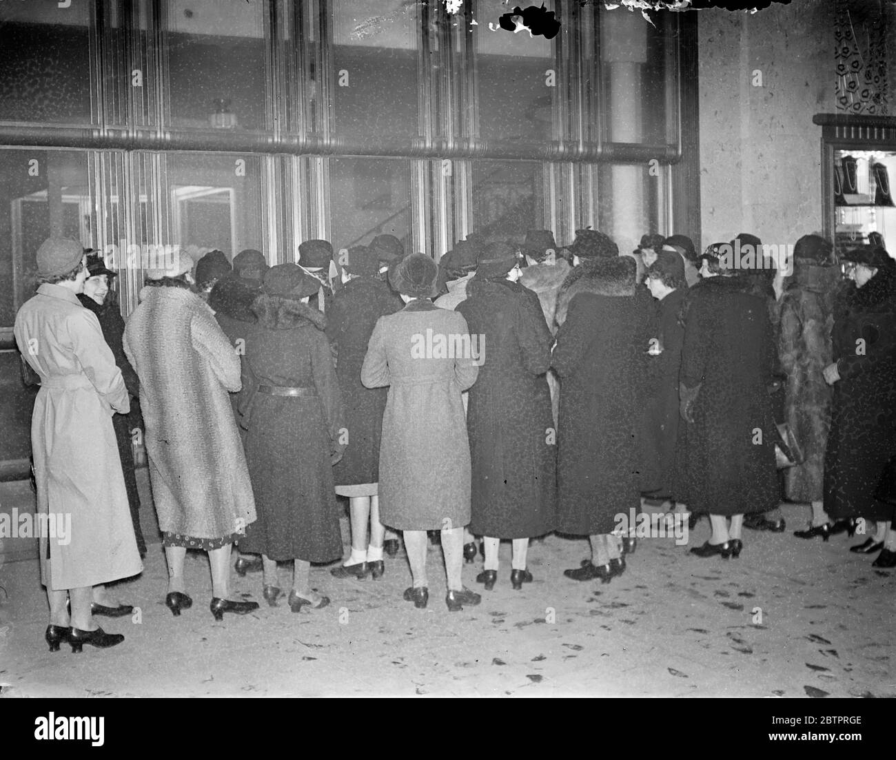 The sales begin in London. Bargain hunters arrived at the big London stores before opening time in order to be in the forefront of the rush when the sales began. Photo shows, the early arrivals waiting outside Barkers, Kensington, at the start of the style. 29 December 1937 Stock Photo