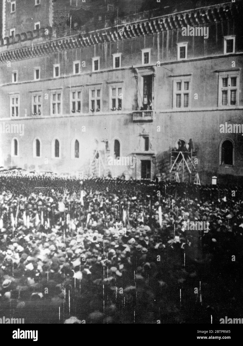 Italy leaves the League. Mussolini statement to frenzied crowd in Rome. Immediately after the Fascist Grand Council meeting, Signor Mussolini stepped on the balcony of the Palazzo Venezia in Rome and announced to a wildly cheering crowd that Italy was leaving the League of Nations. Nearly 100,000 Italians stood in the rain and cheered frenziedly. The speech was broadcast throughout Italy. Photo shows, the scene in the Piazza Venezia as Mussolini (on the balcony of the Palazzo Venezio) announced the decision to leave the League of Nations to the crowd standing in the rain. 12 December 1937 Stock Photo