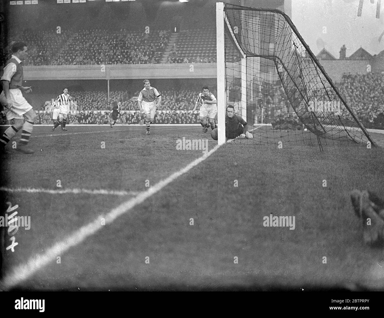 Worrying moment for Arsenal's goalkeeper. Arsenal and West Bromwich Albion met in a first division match at Highbury. Alex Wilson, the Arsenal goalkeeper, watching apprehensively as the ball nearly trickles into the net from a melee in front of goal. 13 November 1937 Stock Photo
