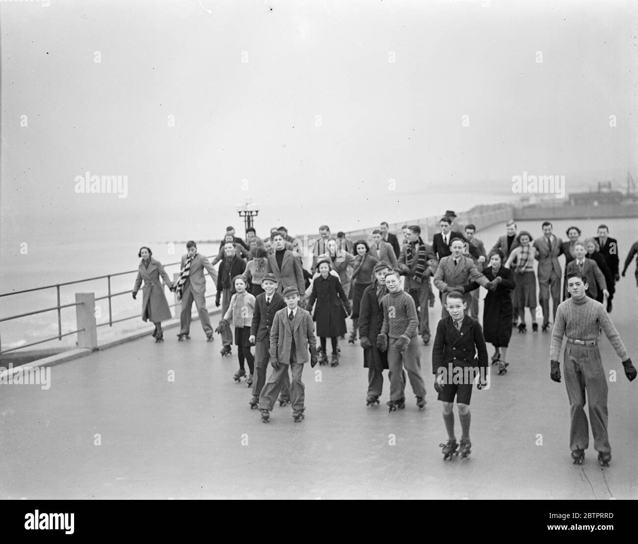Rolling around at Hastings. Young roller skaters enjoying themselves in the crisp air at Hastings, where a roller skating rink is built around the top of the swimming pool. 28 December 1937 Stock Photo
