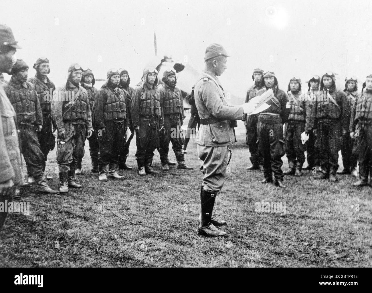 Death announcement! Japanese airmen told their objective on the Shanghai Front. Japanese pilots at a depot on the Shanghai front listening as their commanding officer tells them what 'military objectives' are to be bombed in the raids they are about to undertake. The devastating air raids have been a feature of the big Japanese push in the Shanghai war zone. 27 October 1937 Stock Photo