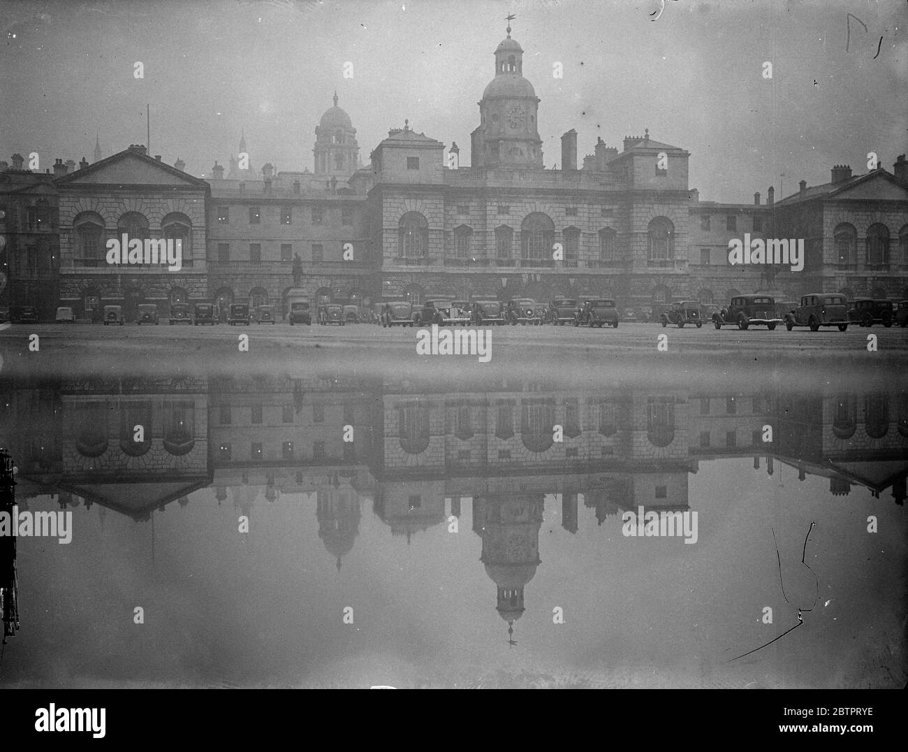 Horse Guards in duplicate. The buildings and parked cars reflected in the rain pools the collected on the Horse Guards parade after a day of incessant rain. 27 October 1937 Stock Photo