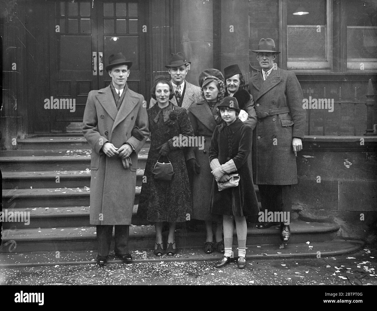 'Apache' touch at London wedding. A distinctive hat, that seams to have a touch of the 'Apache' style, worn by Miss Beatrice Watts (4th in from right) at the wedding of Mr G Walker of Sudbury and Miss B Sherman at the Paddington Register office, London. 27 November 1937 Stock Photo
