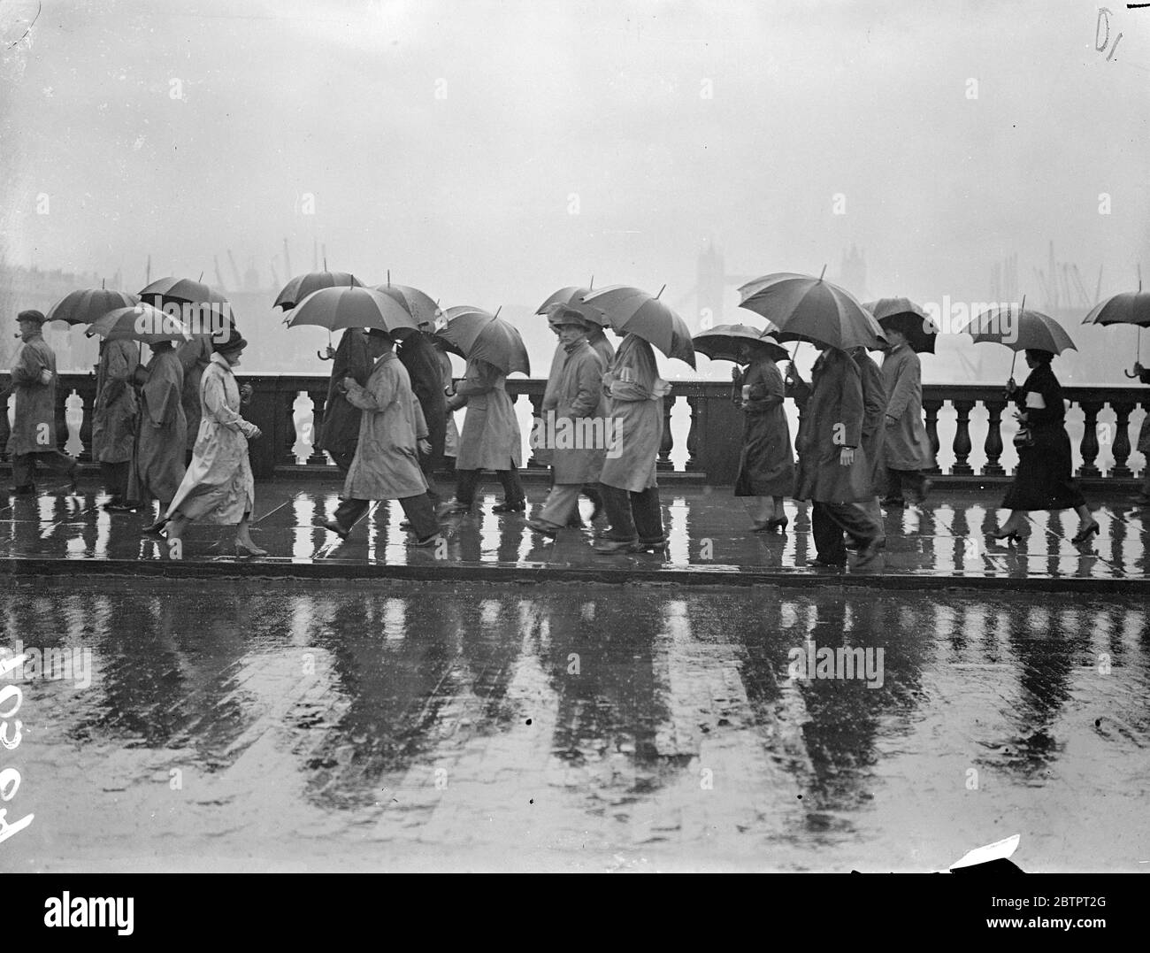 London's Saturday downpour. The driest October 9 in Britain for six years, seems now to have changed its mind, and London has been drenched by torrential rains, the heaviest for many months. Photo shows, pedestrians, carrying over London Bridge under umbrellas. 23 October 1937 Stock Photo