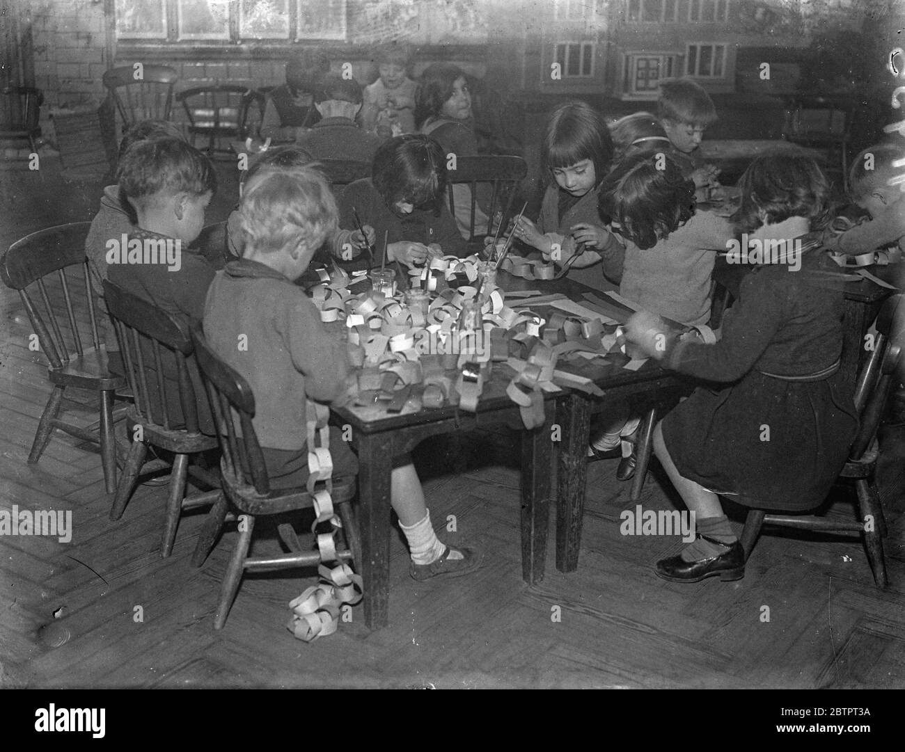 No instruction needed for this!. Children of the Hugh Middleton School, Clerkenwell, EC, engage on the task they like best of all, making paper chains Christmas. 7 December 1937 Stock Photo