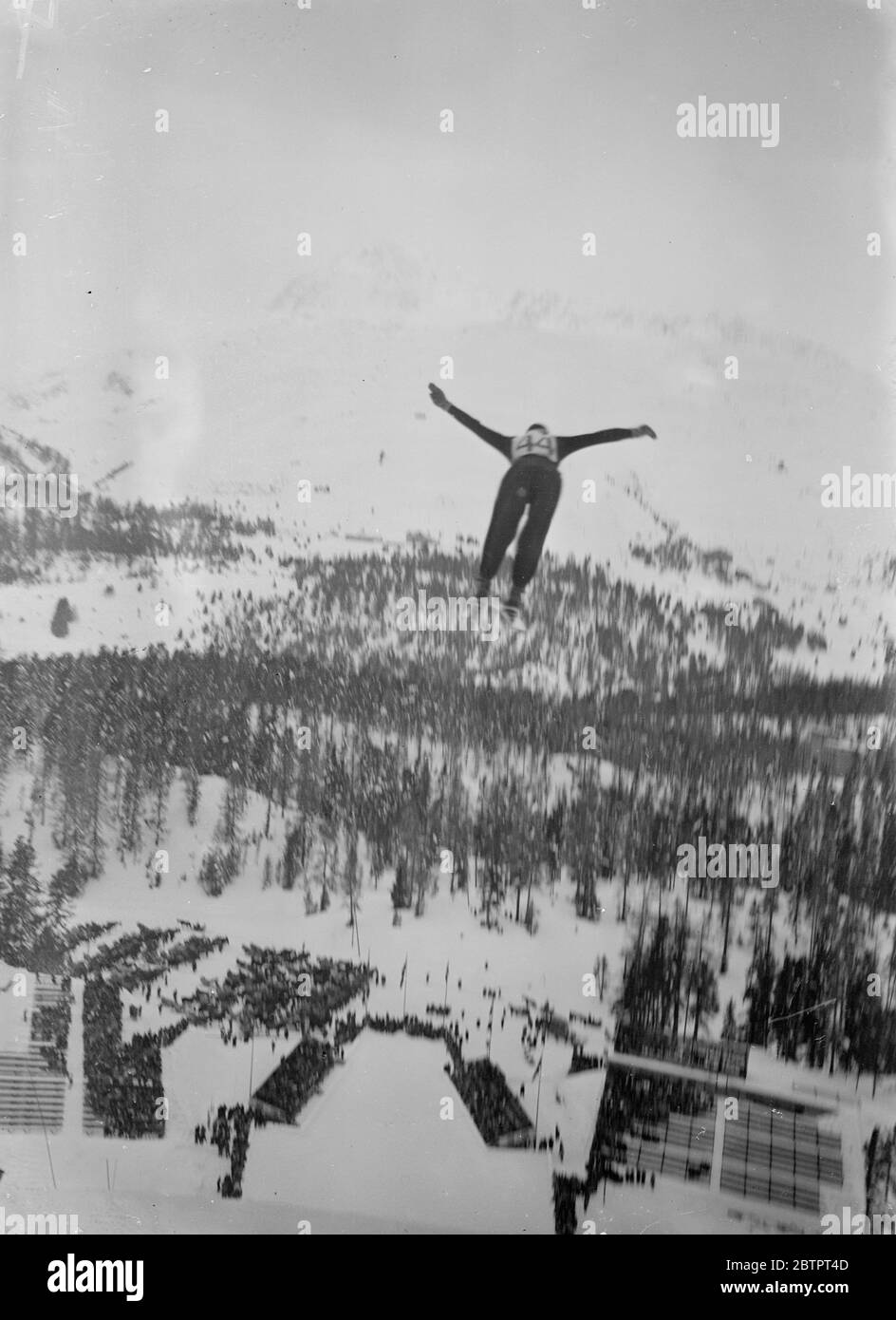 Ski jump through the skies. Buhler Richard, the Swiss champion, appears to hover over the snow covered landscape as he makes a spec track your ski jump at St Moritz, the Swiss resort. 31 December 1937 Stock Photo