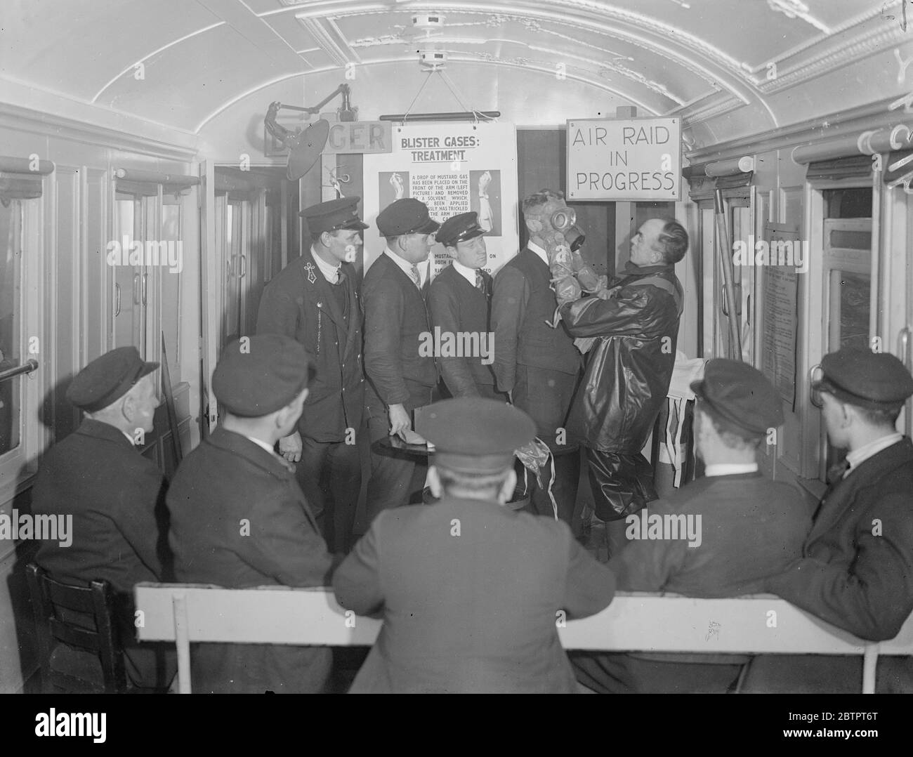 'Guarded' against gas. Anti Air Raid training at Euston. And IMS Air Raid Precaution Mobile Instructional Unit was on view at Euston station, London. The unit consist of two vehicles, one a lecture coach and the other a decontamination coach. It has been provided by the IMS Railway as part of a scheme for the training of their staff in Air Raid Precautions. The mobile unit is soon to undertake a tour of the IMS system in England, Scotland and Wales. They railway intends to train nearly 23,000 of their 230,000 workers in anti air raid work. Photo shows, railwaymen being fitted with gas masks. A Stock Photo