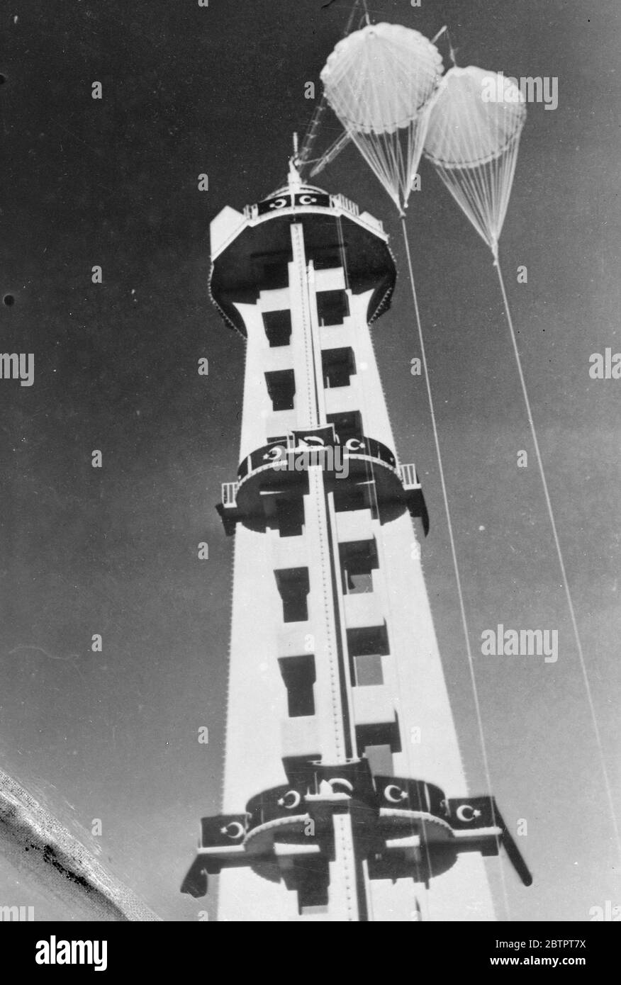 Parachute craze reaches Turkey. The modern craze of the captive parachute tower has spread from Russia and France to Turkey. In Ankara, the capital, young Turkey can now get a thrill and valuable instruction by a leap from the tall white tower, which has been erected in the city. The tower as to parachutes, which are controlled by machinery. 5 December 1937 Stock Photo