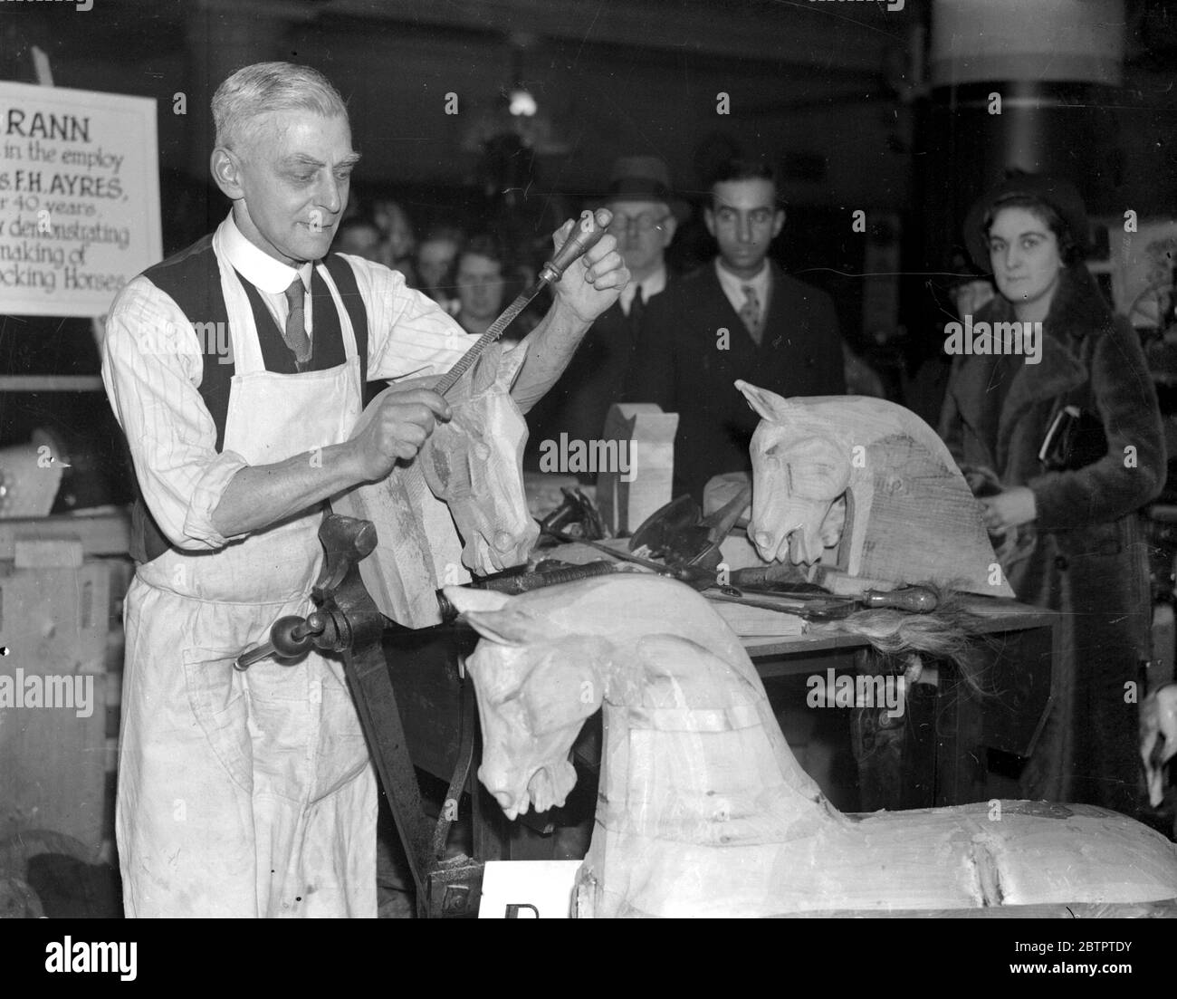 (74 Hillfield Avenue, N.8) Mr Rann, for 50 years a maker of wooden horses, demonstrates his craft at Selfridge's. 10 March 1936 Stock Photo