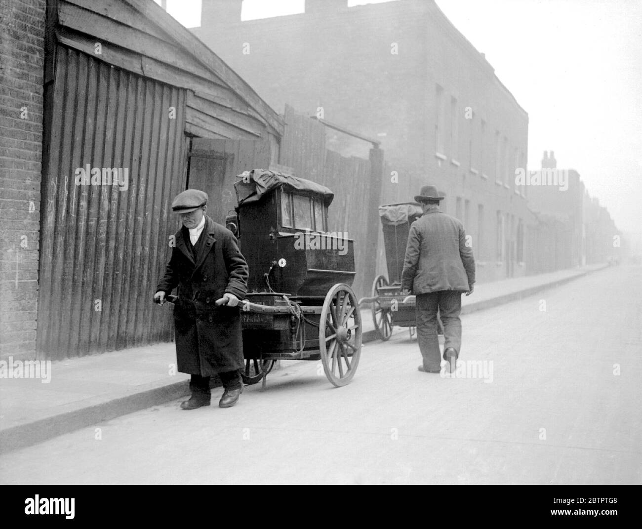 UK London Labourer pulls away an organ from the Faccini Barrel Organ Depot in Ernest Street, Stepney in the East End of London. The man with his back to the camera on the right is Bartholomew Faccini, brother of the owner of the depot, Albert Faccini. The depot hired out the organs for a shilling to half a crown a day, depending on the number of tunes that the organ could play. 1933 Picture by John Topham Stock Photo