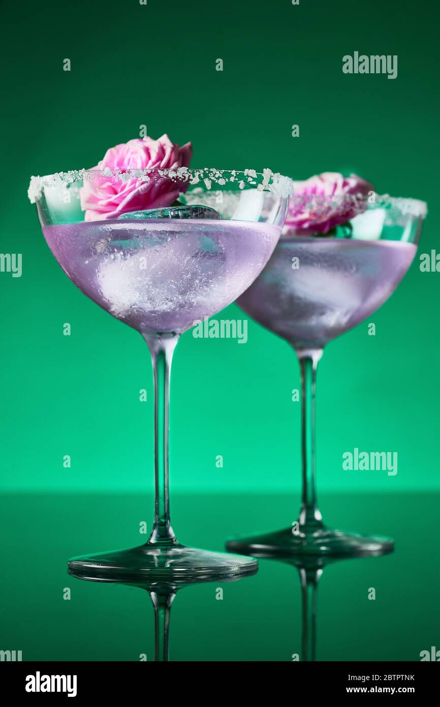 Two tall cocktail glasses with pink gin and tonic garnished with large  crystals of salt on an edge of a glass, large piece of ice, peppermint  Stock Photo - Alamy