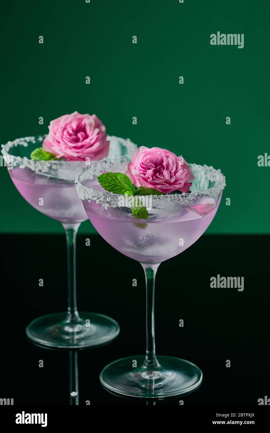 Two tall cocktail glasses with pink gin and tonic garnished with large  crystals of salt on an edge of a glass, large piece of ice, peppermint  Stock Photo - Alamy