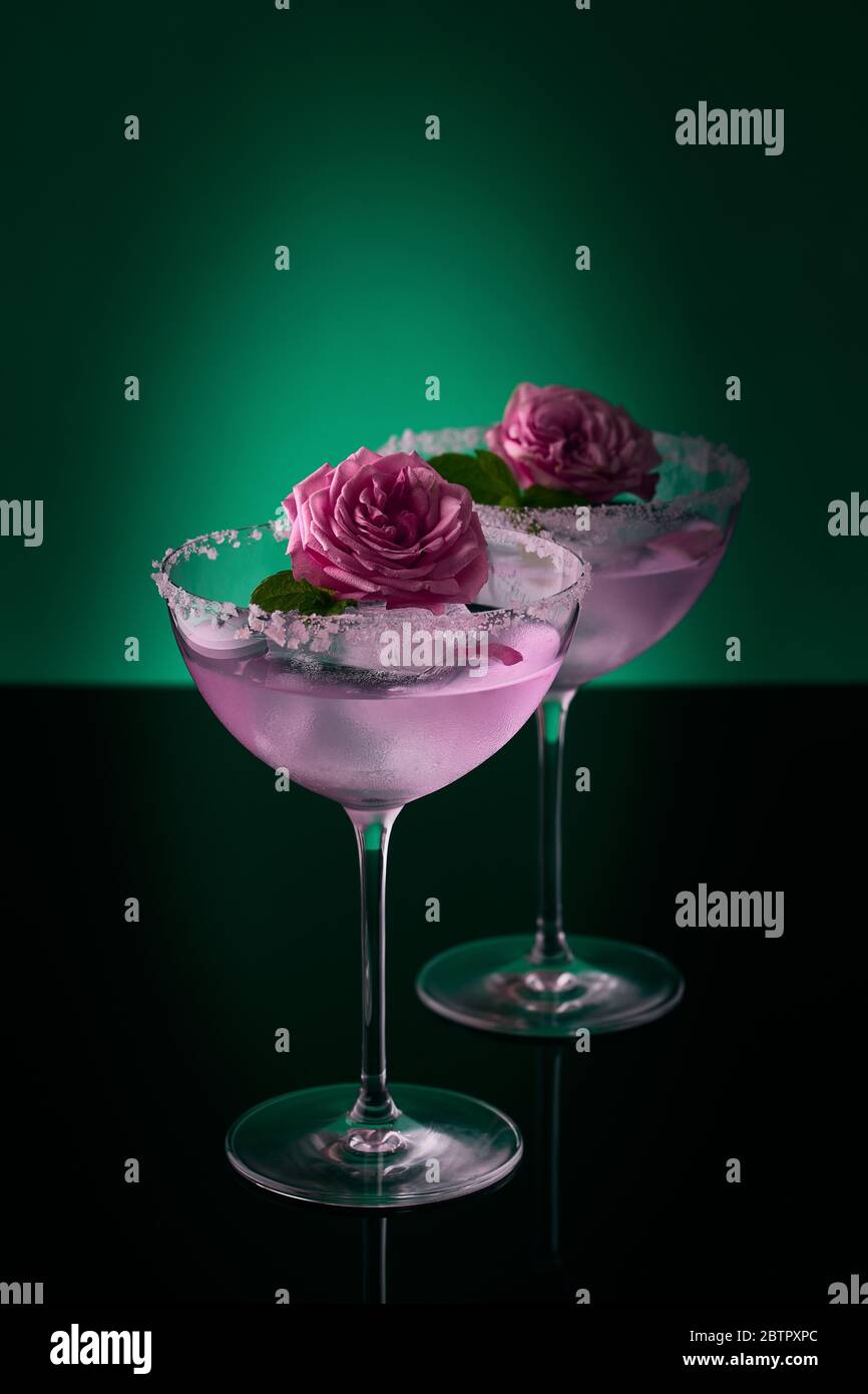 https://c8.alamy.com/comp/2BTPXPC/two-tall-cocktail-glasses-with-pink-gin-and-tonic-garnished-with-large-crystals-of-salt-on-an-edge-of-a-glass-large-piece-of-ice-peppermint-2BTPXPC.jpg