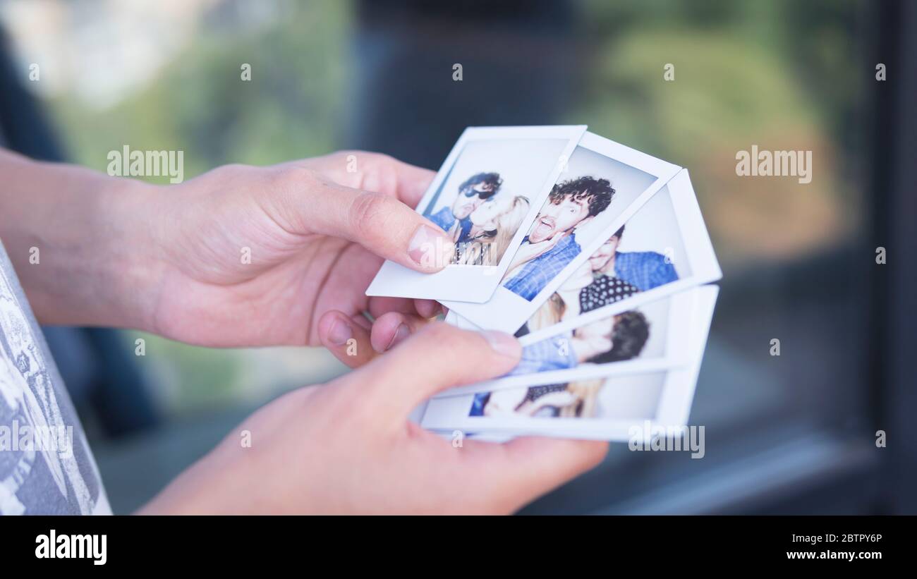 Close-up of man holding in the hand printed photos with picture of young couple. Concepts of happy memories, romantic and love Stock Photo