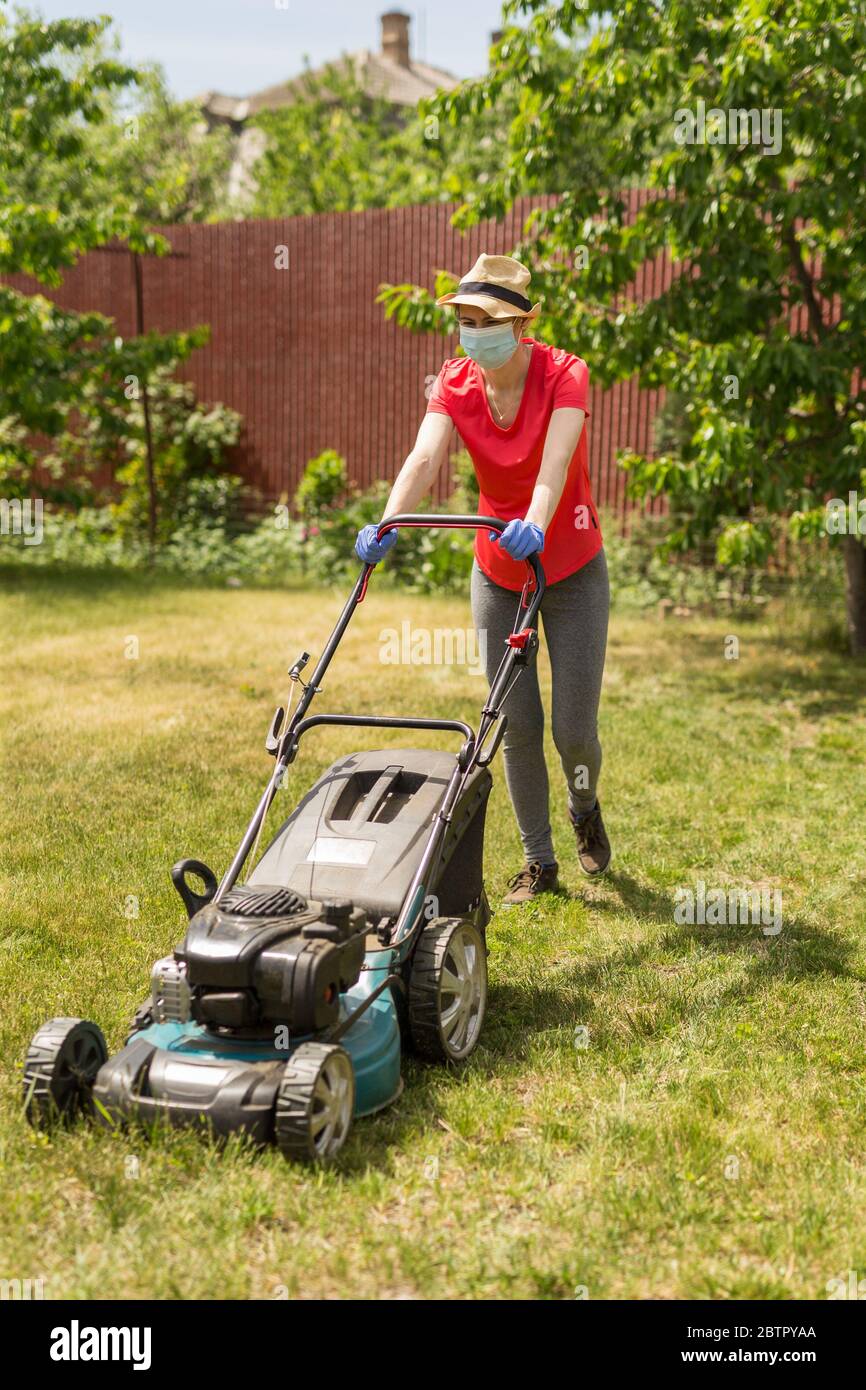 https://c8.alamy.com/comp/2BTPYAA/a-woman-in-her-backyard-mowing-grass-with-a-lawn-mower-on-a-sunny-day-at-home-wearing-a-surgical-mask-because-of-the-coronavirus-epidemic-2BTPYAA.jpg