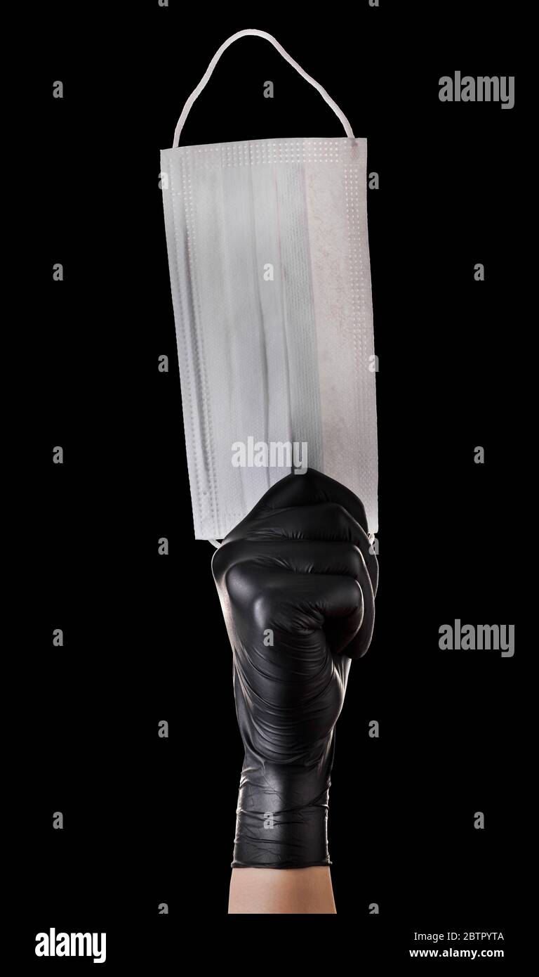 Hand in black gloves holding disposable face mask isolated on black ...
