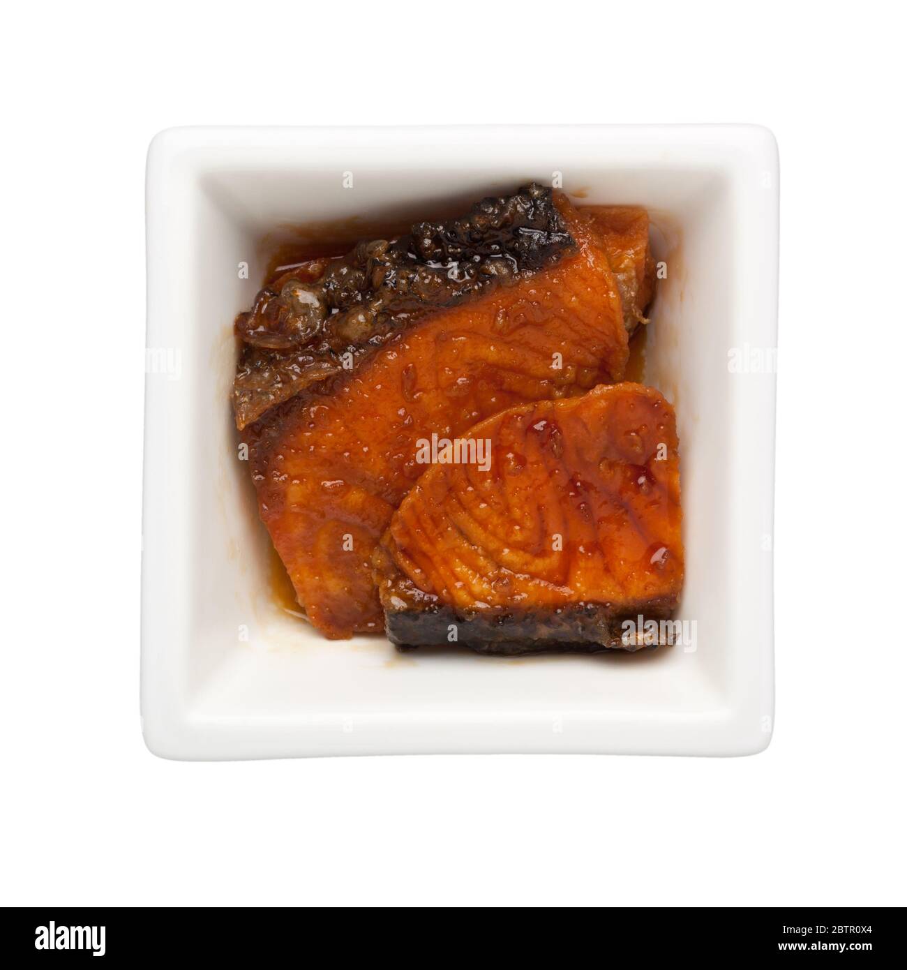 Japanese food - Pan grilled teriyaki salmon fillet in a square bowl isolated on white background Stock Photo