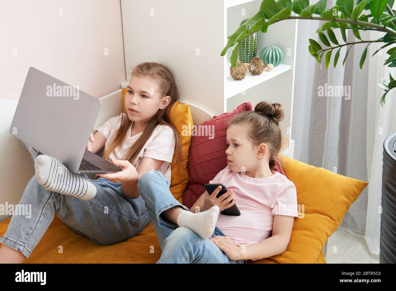 Two little sisters using laptop lying on bed at home Stock Photo - Alamy