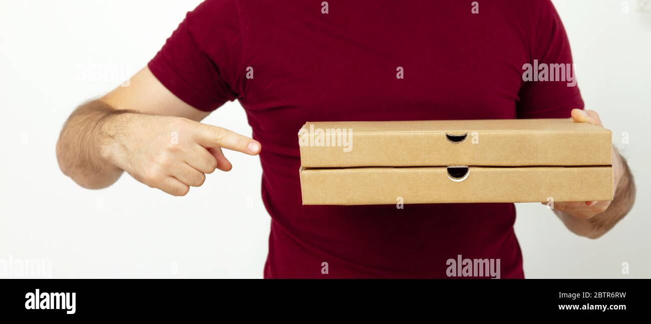 Delivery man in red t-short holding cardboard boxes of pizza on white background. Pizza delivery. Courier home delivery. food order pizza boxes Stock Photo