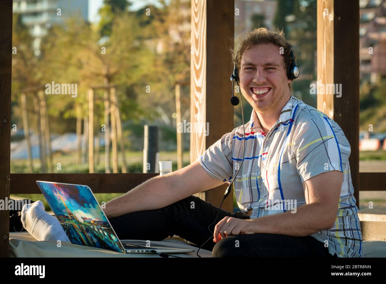 One man using laptop and headset outdoors at a beach Stock Photo