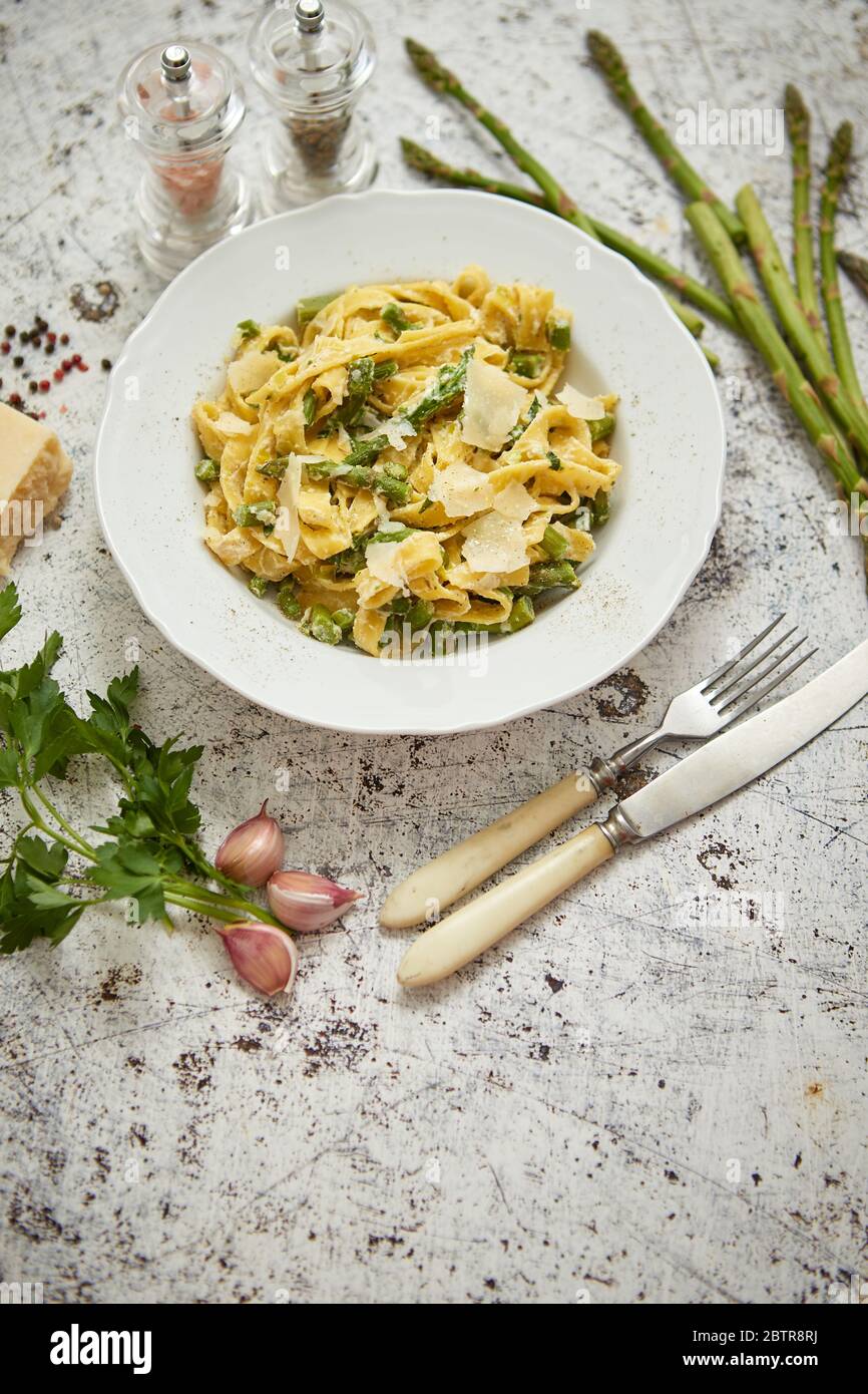 Tagliatelle pasta with creamy ricotta cheese sauce and asparagus served white ceramic plate Stock Photo