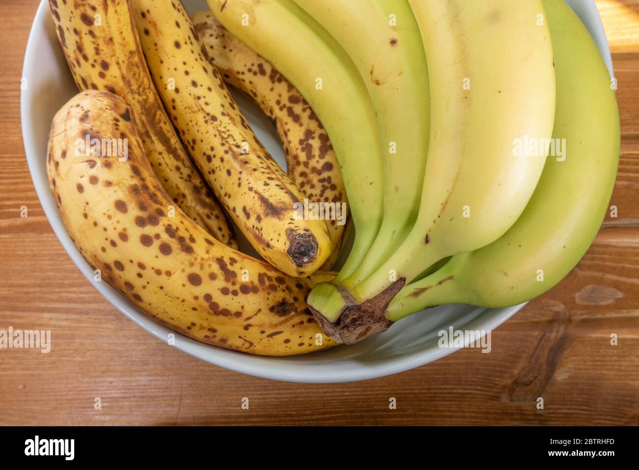 A bunch of unripe / green bananas alongside some ripe bananas in a
