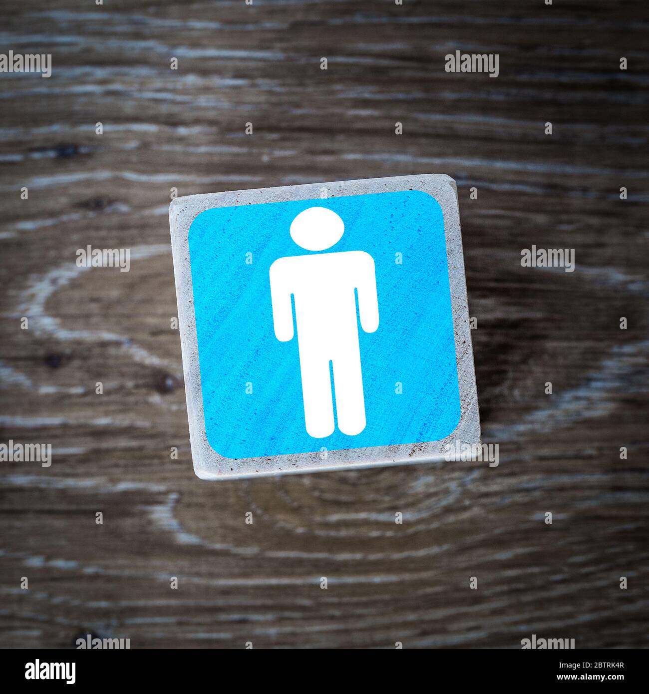 A blue men's toilet sign, symbol or icon on a wooden block with a wood background and copy space Stock Photo