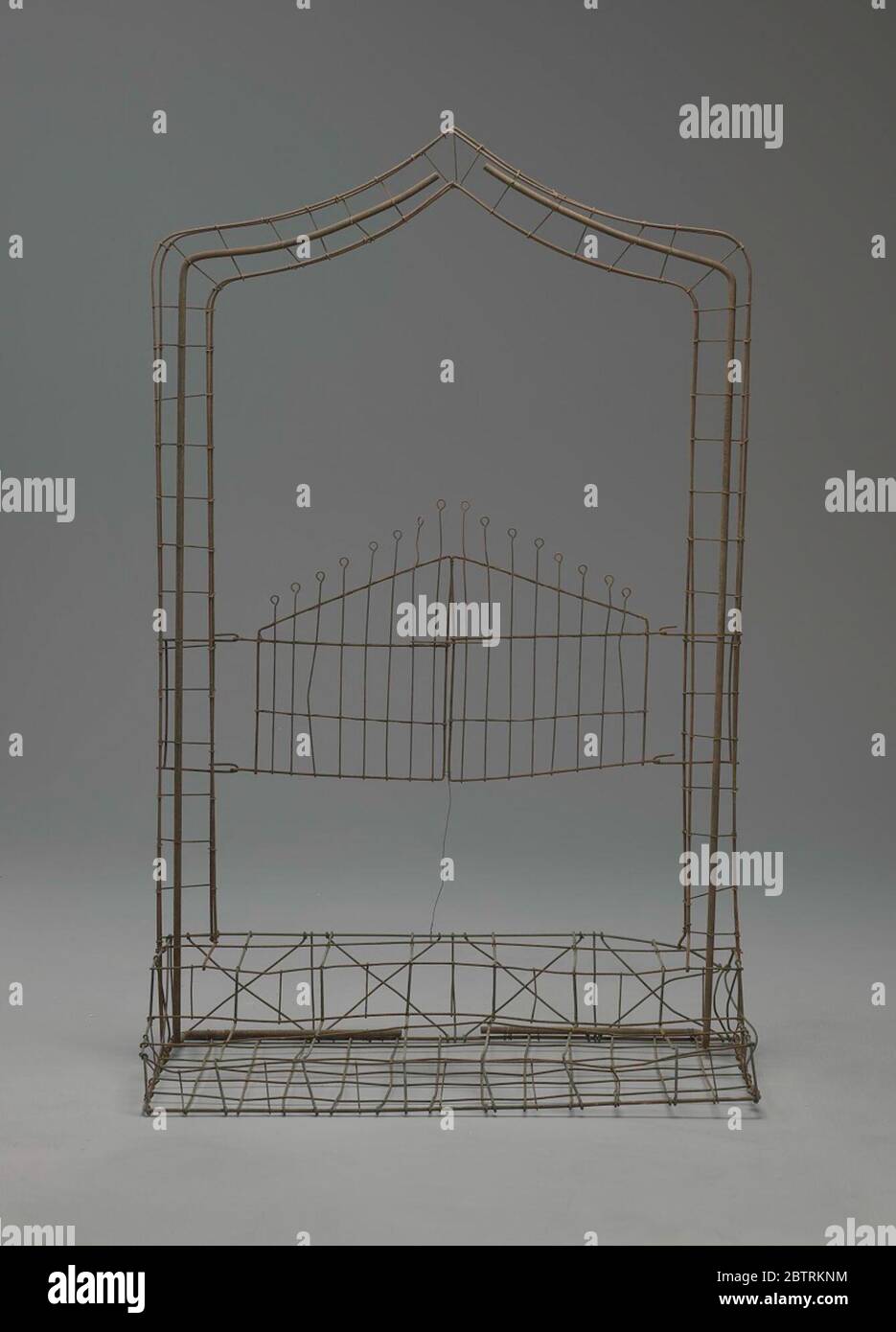 Wire frame gates ajar. The Gates Ajar or Gates of Heaven set piece was an especially elaborate design and very popular in the late nineteenth century and early twentieth century. It generally ranged from two to four feet high with either pointed or rounded arches over a pair of gates. Stock Photo