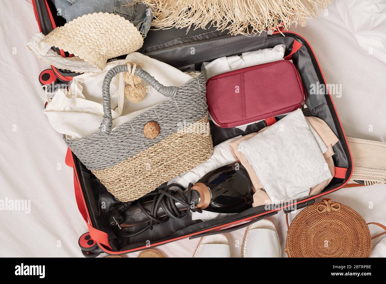 Above view of womens stuff packed into suitcase on bed, preparing