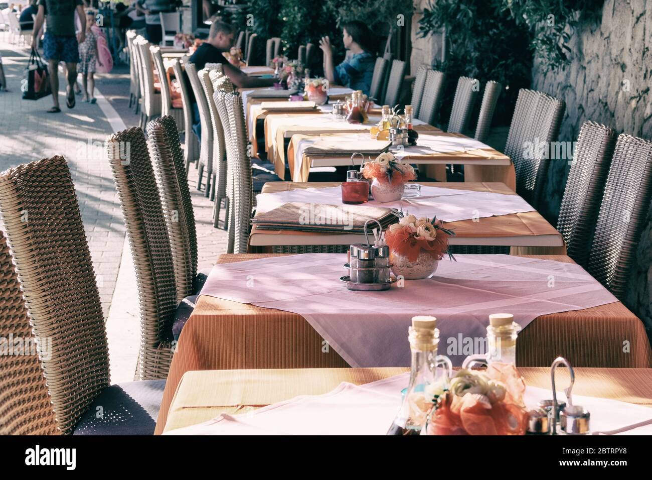 Table setting in modern restaurant. Decorated holiday table on outdoor terrace of cafe. Patio in city in suny summer. Stock Photo