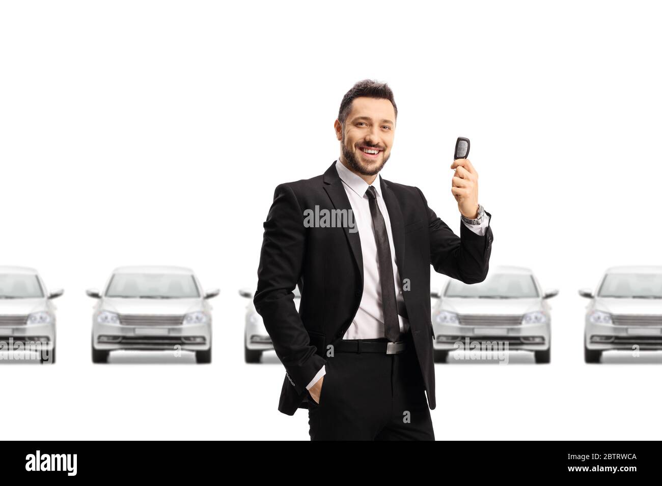 Car salesman holding a car key in front of a row of silver cars