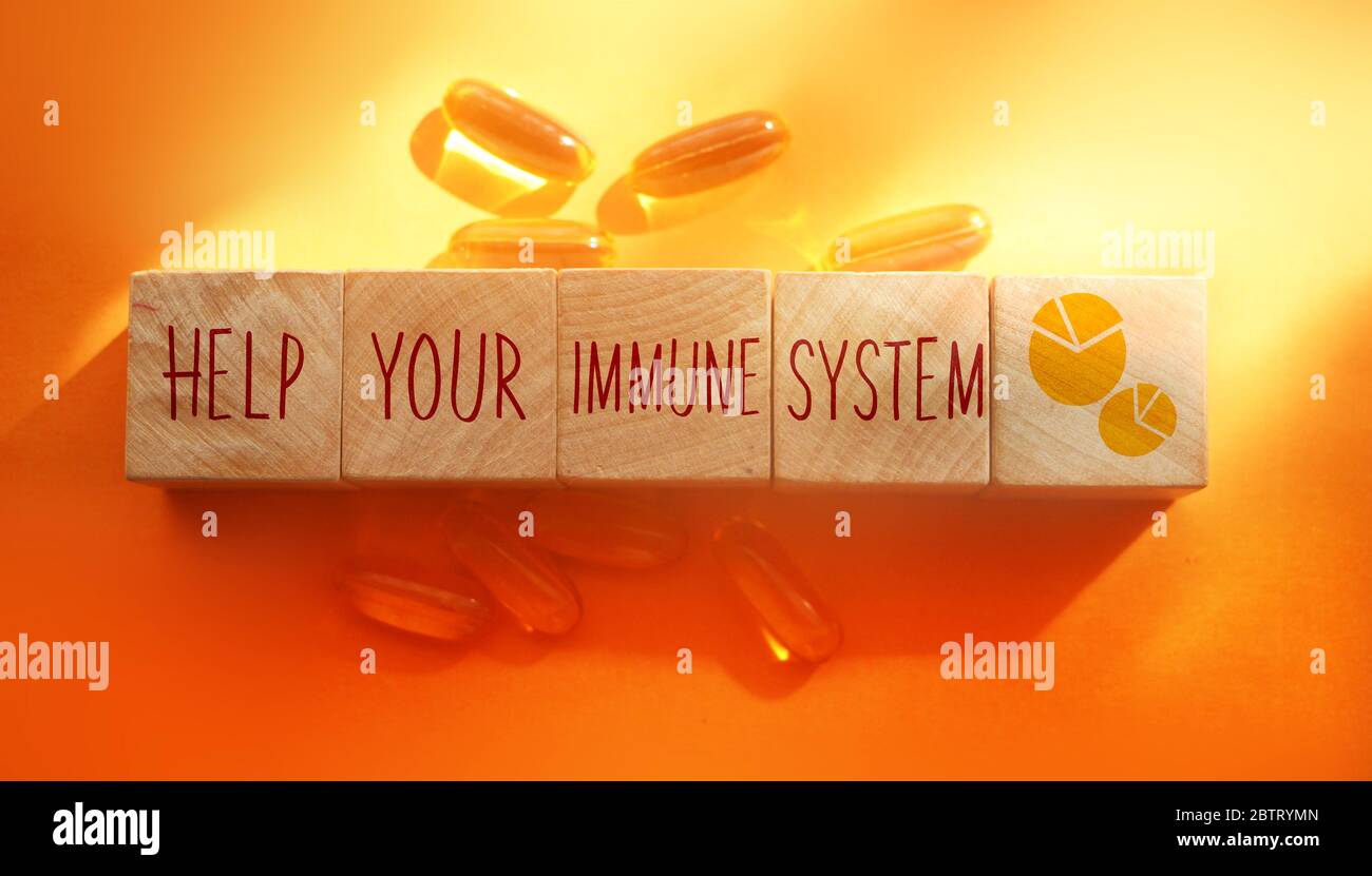 Help your immune system words made with wooden building blocks and Omega-3 pills on orange background. Healthcare concept Stock Photo