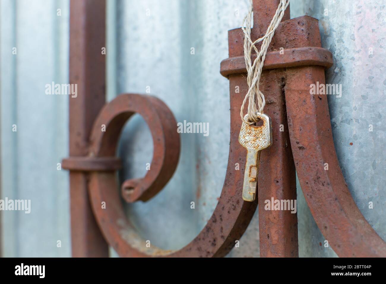 Old rusty key hangs on the old fence. Lost keys and opportunities concept. Close up with copy space for text. Stock Photo