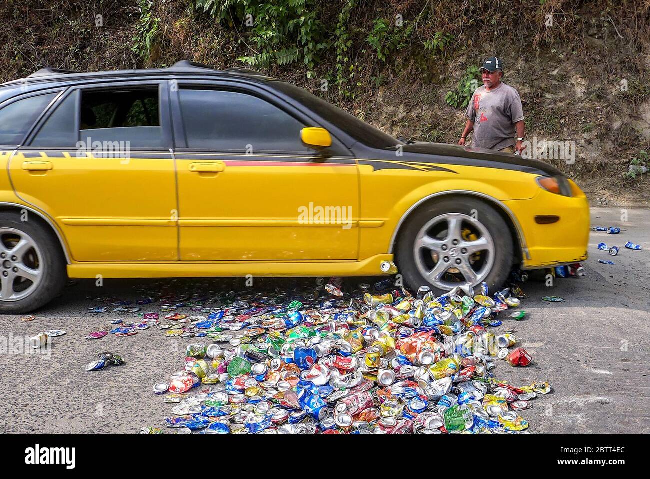 In San Andrés Semetabaj, a municipality in Sololá, Guatemala, Alirio López, 63, places soda cans on a road so that passing cars will crush them. Alirio recycles the cans into kitchen utensils. (Brenda Leticia Saloj Chiyal, GPJ Guatemala) Stock Photo
