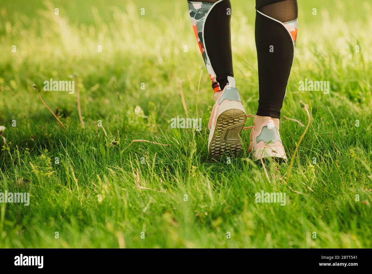 The girl runs on the green grass. Part of the body. Soft focus. Copy space Stock Photo