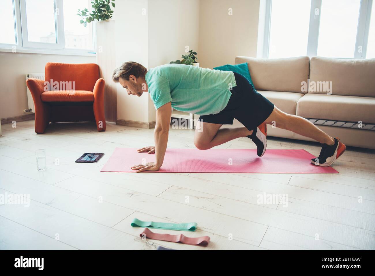 Caucasian man doing sport exercises at home while looking at the tablet on the floor Stock Photo