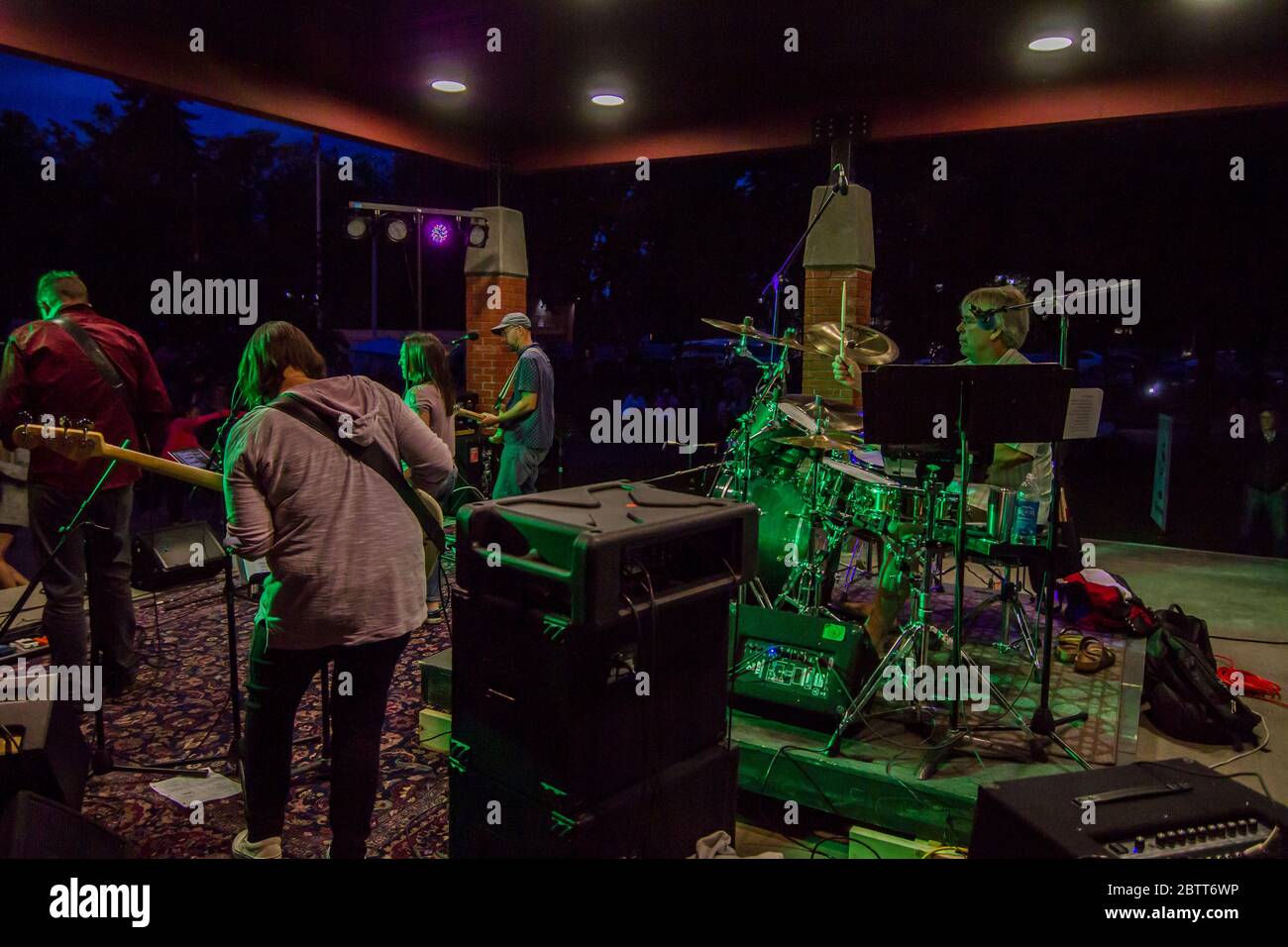 Rock band on stage, in concert, singer, bass guitar, lead guitar and drums,  shot from behind. Stock Photo