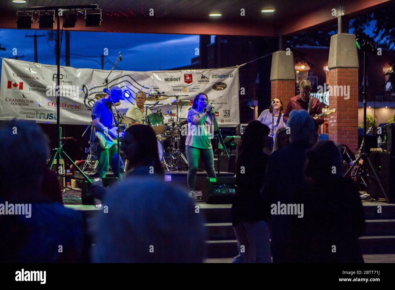 Rcok band in concert, with people dancing in forefground. Singer, bass guitar, lead guitar and drums Stock Photo