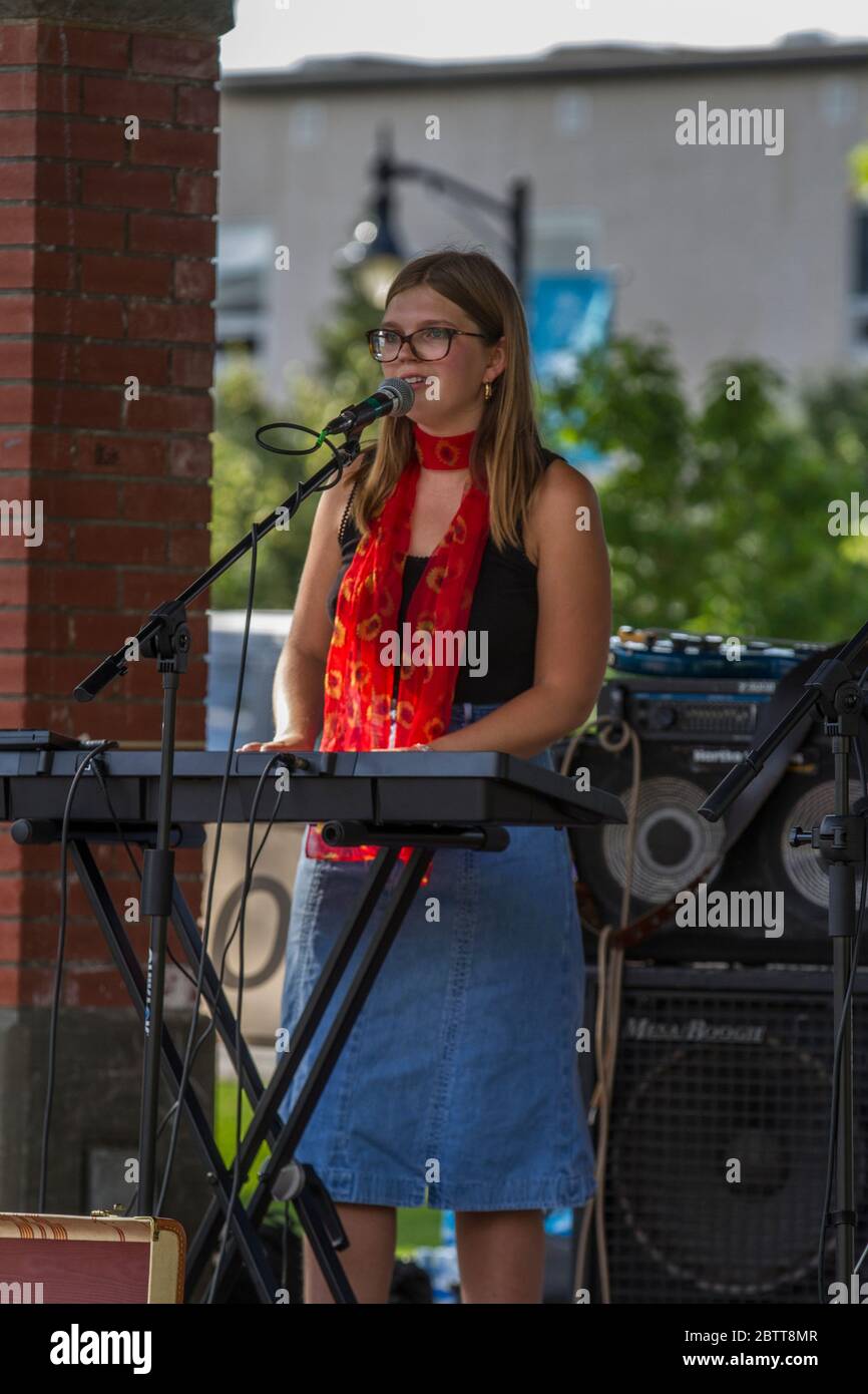 Attractive female, in outdoor concert, singing and playing keyboards. Stock Photo