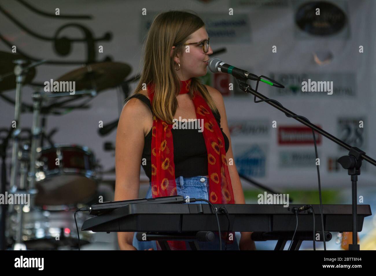 Attractive female, in outdoor concert, singing and playing keyboards. Stock Photo