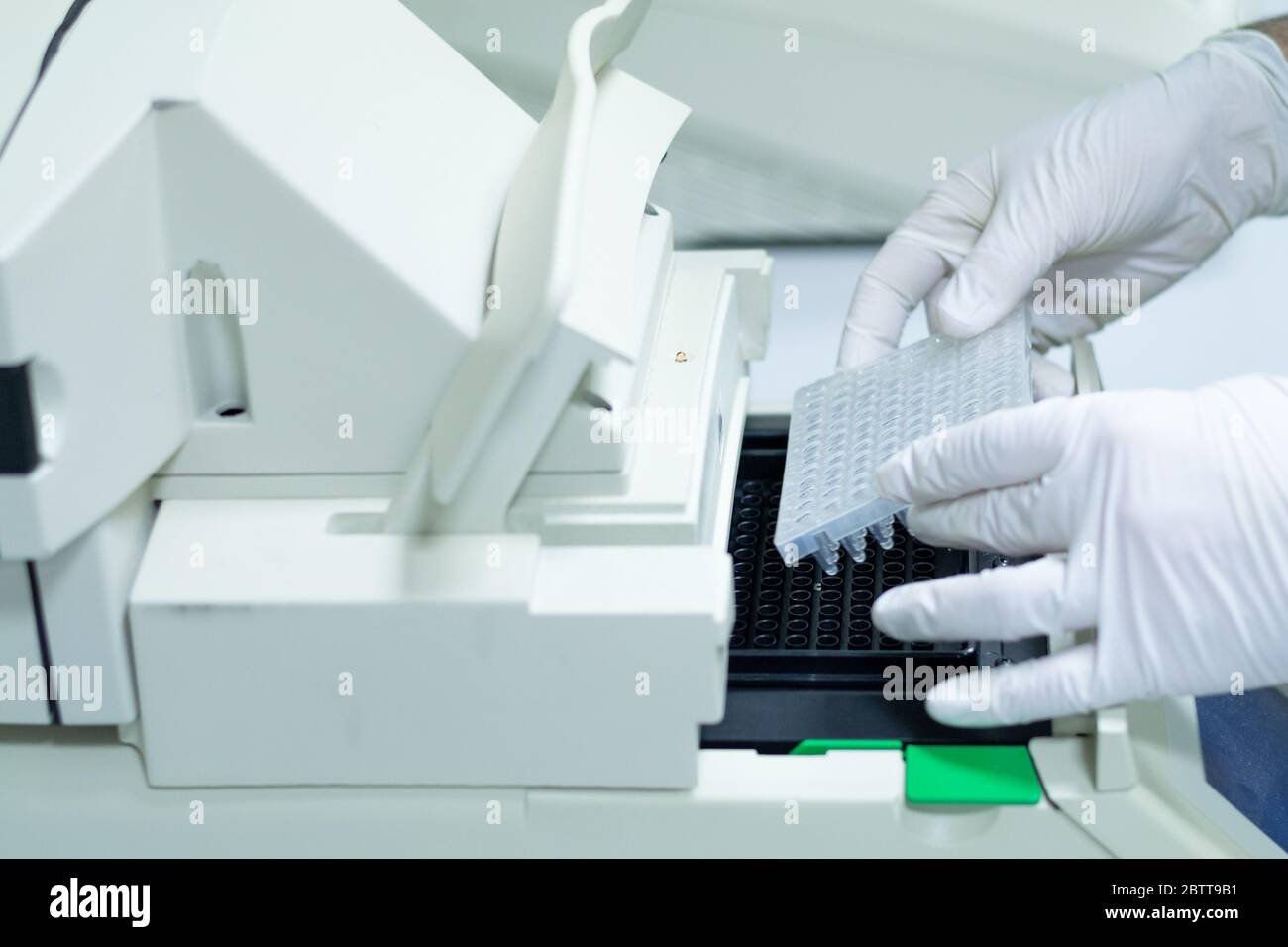 Researcher or scientific introducing a 96 wells plate in quantitative PCR machine/ Thermocycler for DNA or RNA quantification in a biotechnology labor Stock Photo