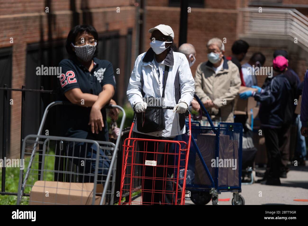People wait in line to receive donated food at the Queensbridge Houses