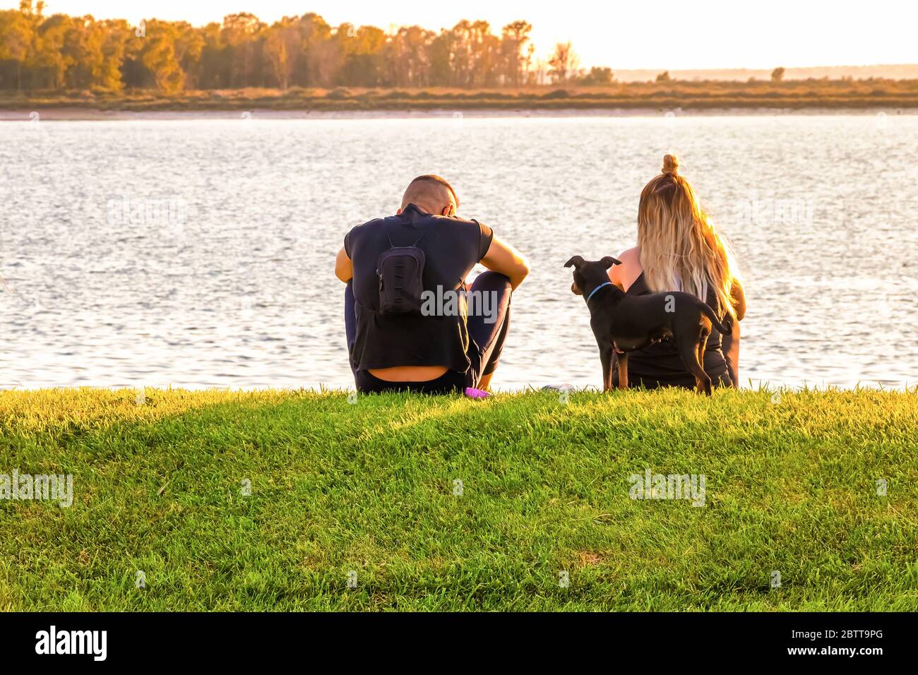 Couple sitting on the grass and enjoying the sunset Stock Photo