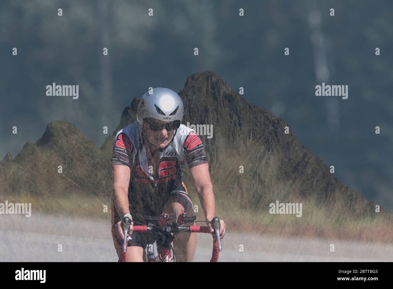 Scenic Bike Race, single rider, in full racing gear and uniform. Mountain background Stock Photo