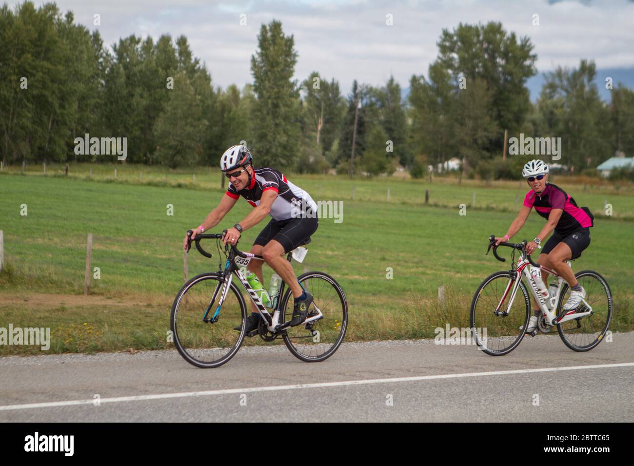Scenic Bike Race, 2 riders, in full racing gear and uniform. Race goes thru farmland and the mountains. Stock Photo