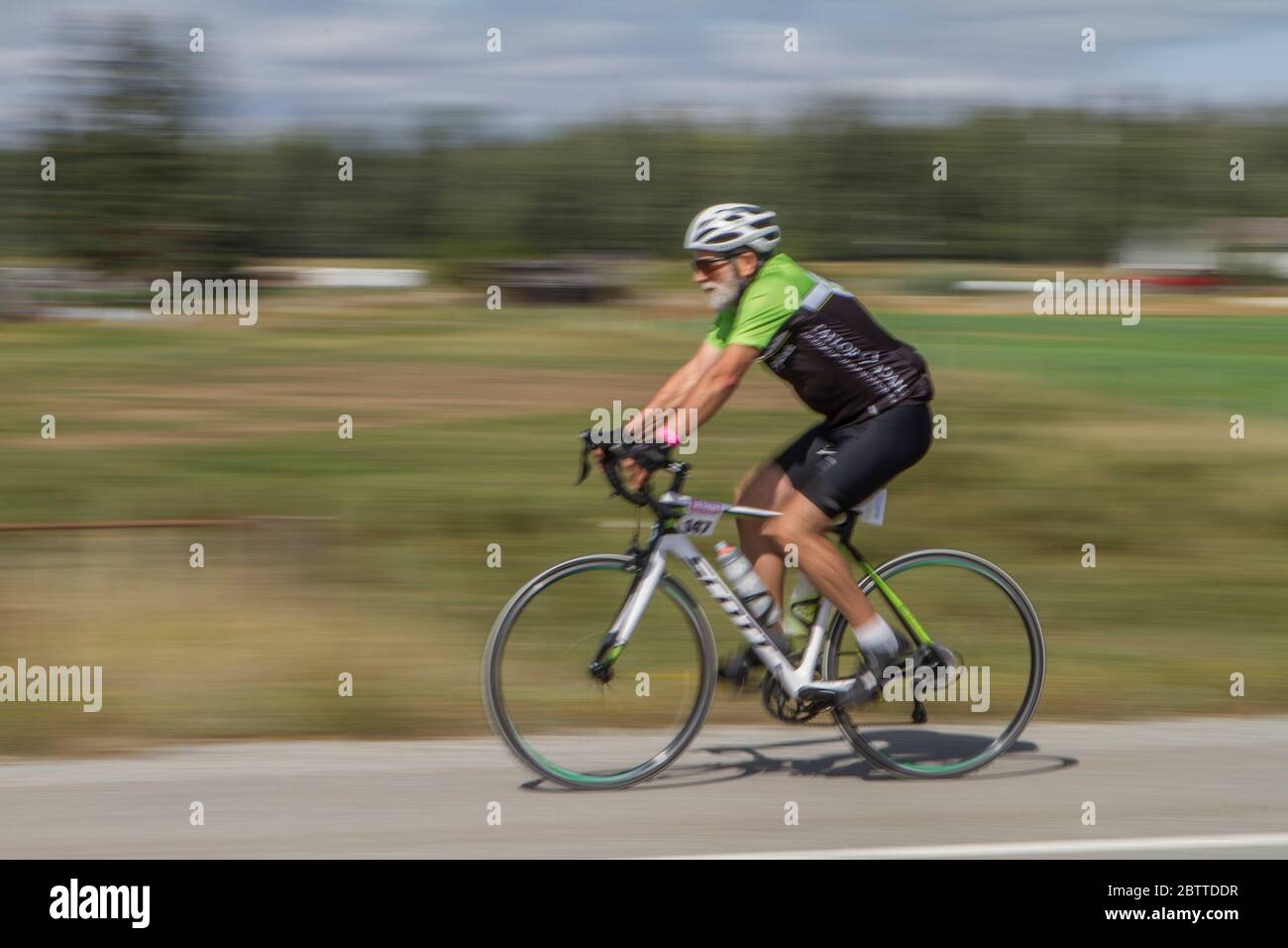 Scenic Bike Race, single rider, in full racing gear and uniform. Blurred background. Stock Photo