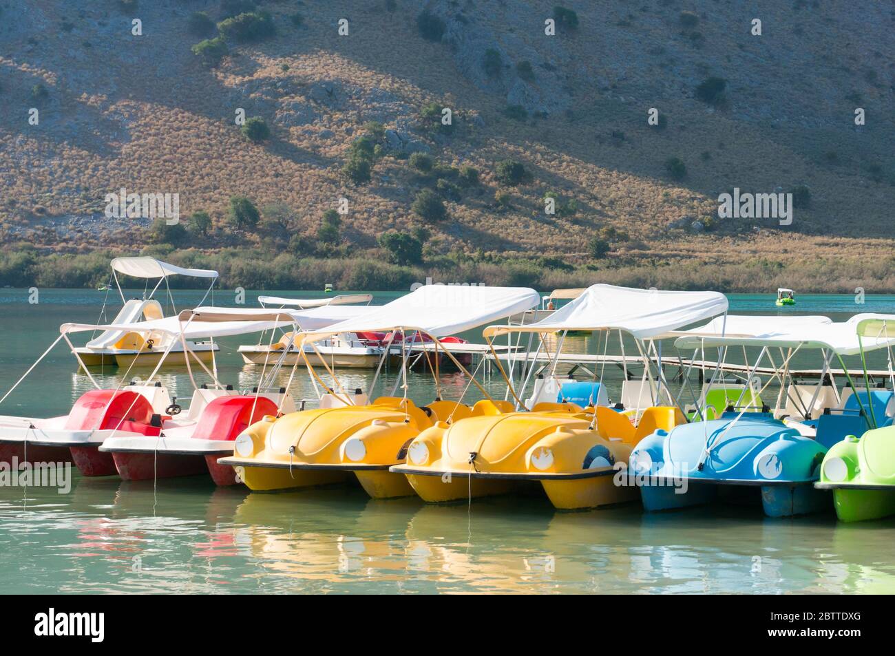 Kournas lake, Crete, Greece-October 13, 2019: colorful water catamarans near the shore of a magnificent lake in the mountains on a sunny summer day. Stock Photo