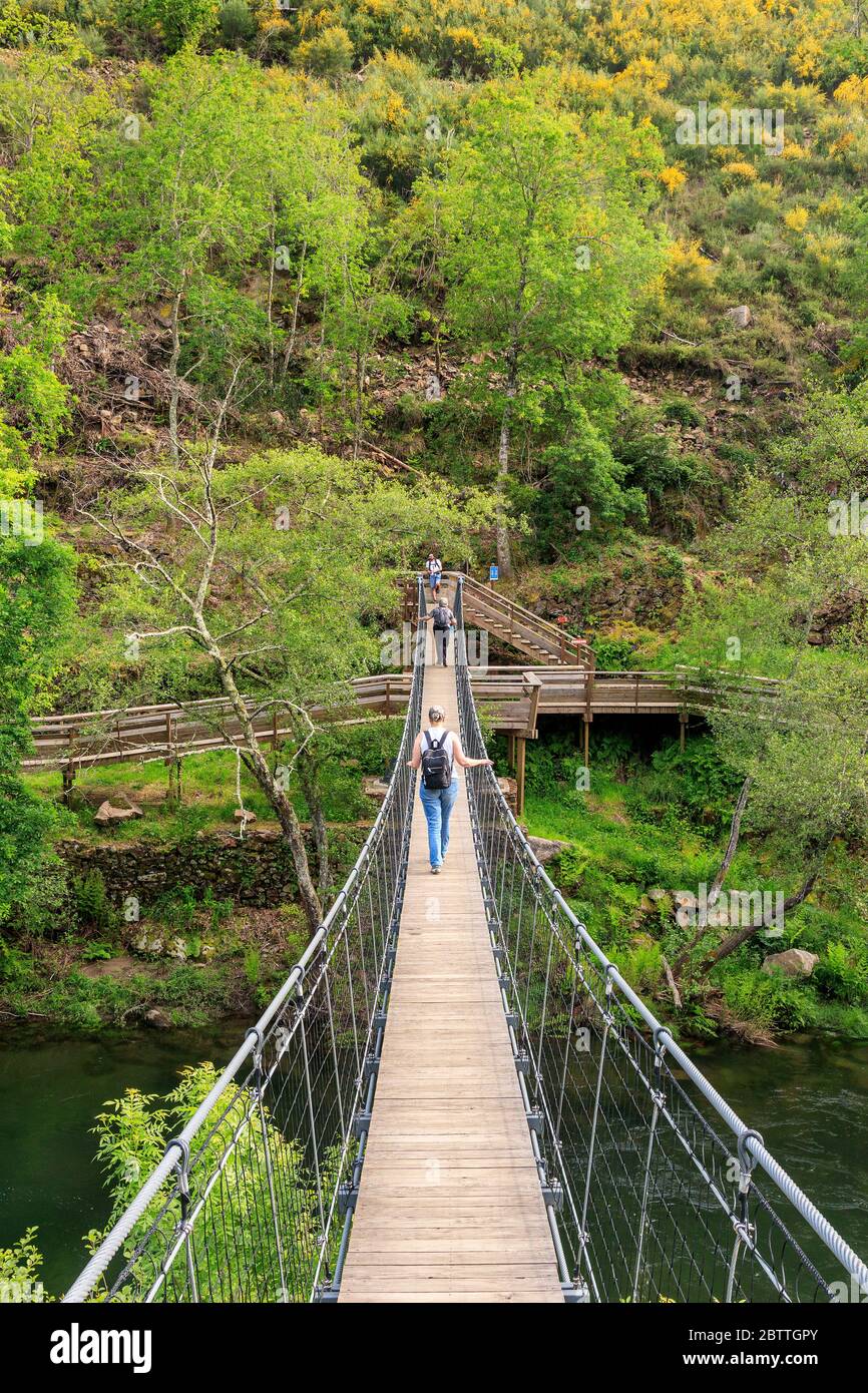 Arouca, Portugal - April 28, 2019: Suspended pedestrian bridge over the Paiva river, giving access to the Paiva walkways with people to cross. Stock Photo
