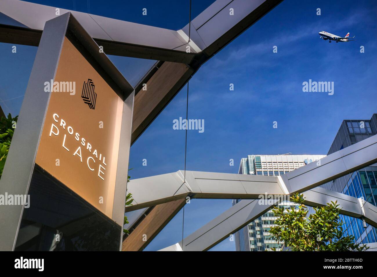 Canary Wharf Crossrail Place Roof Garden & view through windows to office towers with Embraer 190 BA CityFlyer aircraft on approach to City Airport UK Stock Photo